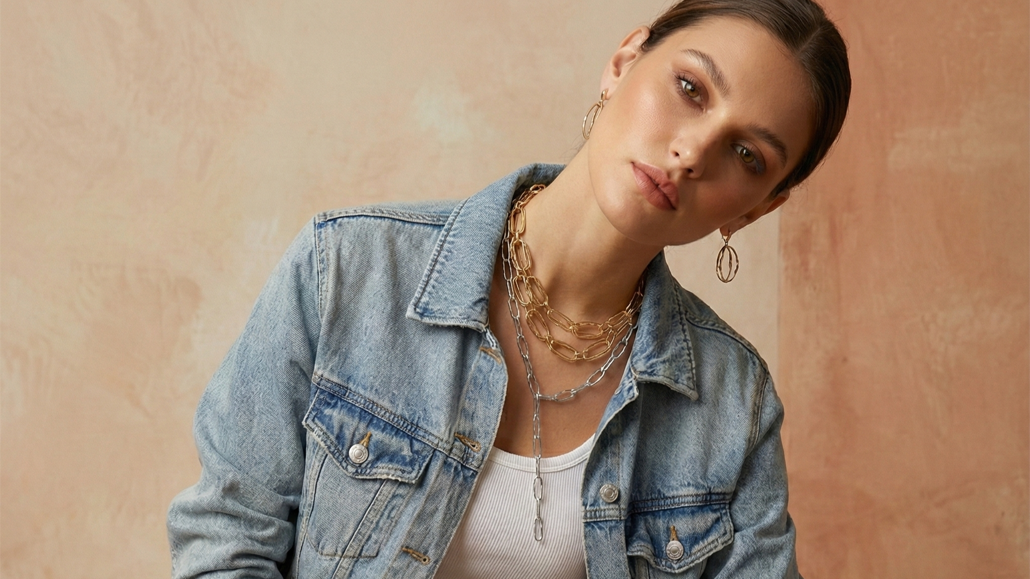 New Arrivals collection featuring a model wearing elegant gold jewelry and pearl accessories.