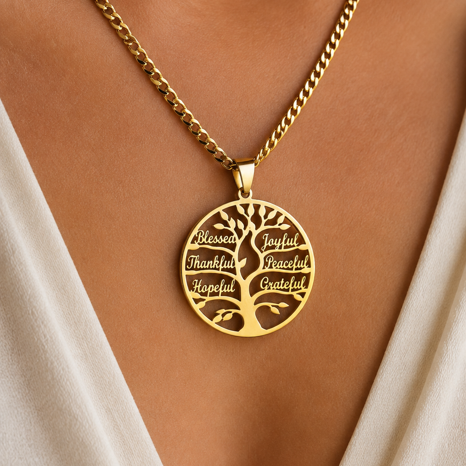 A gold family tree pendant necklace worn on a model's neck, featuring engraved words like 'Blessed', 'Grateful', 'Thankful', 'Happy', and 'Beautiful' on a gold chain.